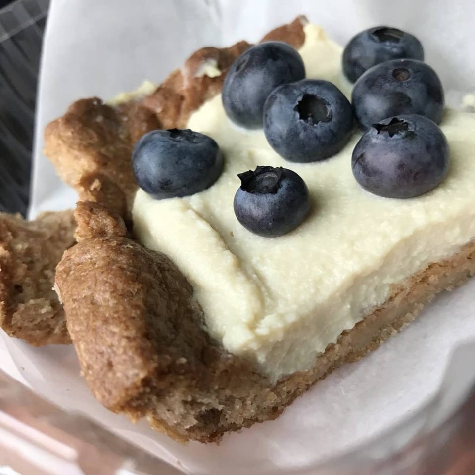 A healthy blueberry tart from Green Symphony with a creamy white filling and golden crust.