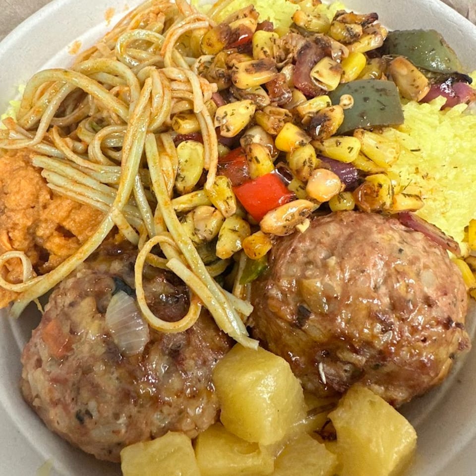 A healthy Green Symphony meal with meatballs, pasta, corn, peppers, and pineapple in a white bowl.