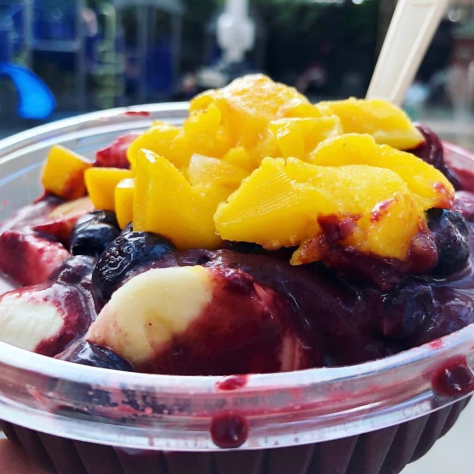 Close-up of a vibrant acai bowl topped with fresh mango, blueberries, and banana slices.