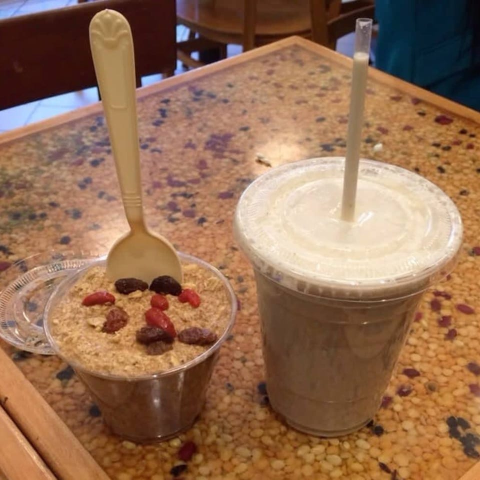 A Green Symphony smoothie and a healthy parfait with berries and nuts on a speckled table.